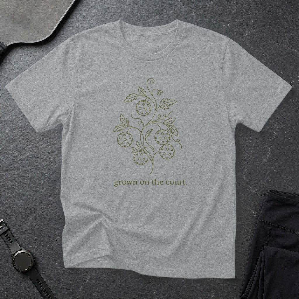 Gray t-shirt with a minimalist pickleball graphic and "grown on the court" text.
