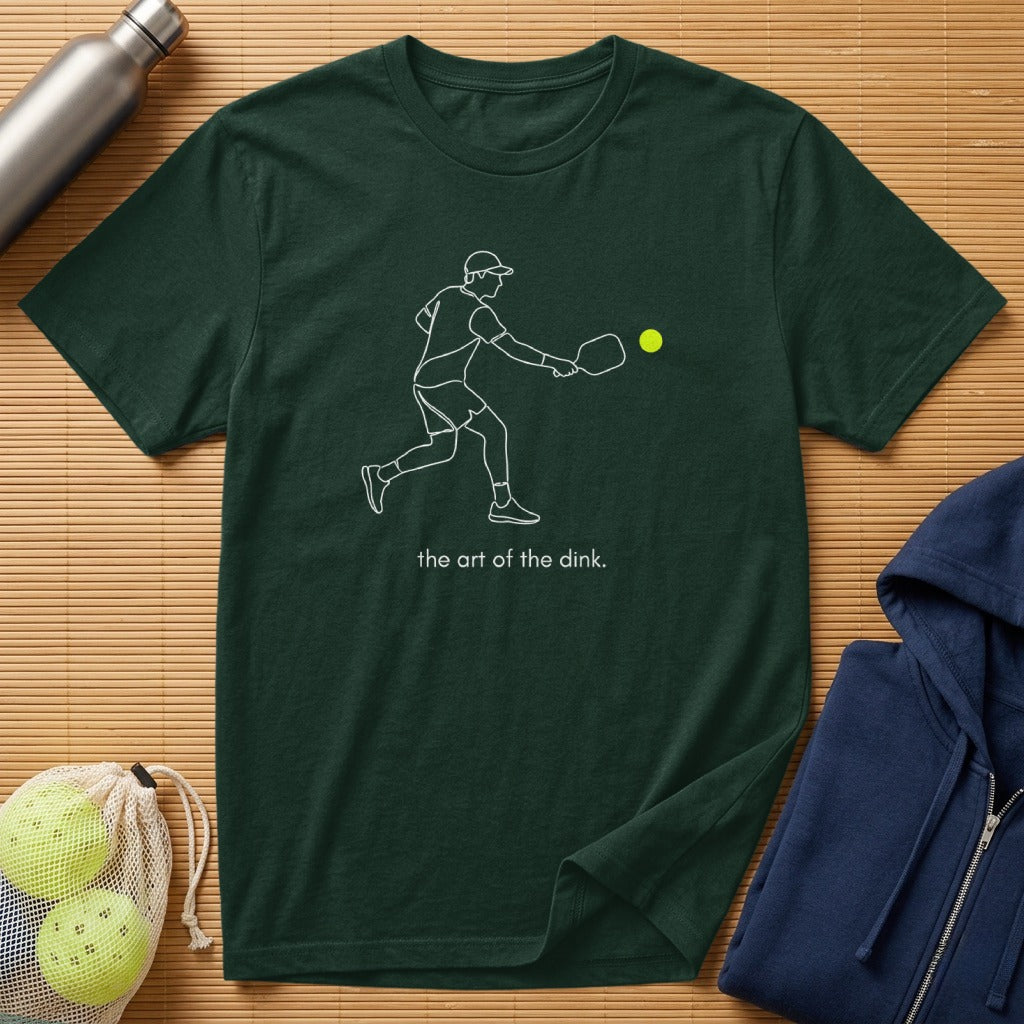 Dark green t-shirt with minimalist pickleball player graphic and "the art of the dink" text.