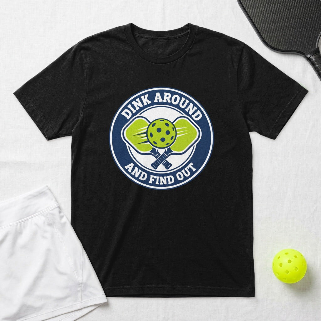 Black t-shirt with a circular logo featuring pickleball paddles, balls, and text.