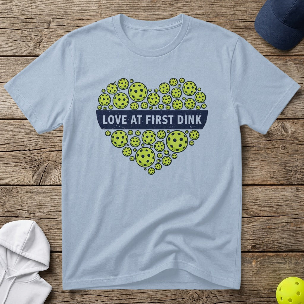 Light blue t-shirt with a heart made of pickleballs and text "Love at First Dink".