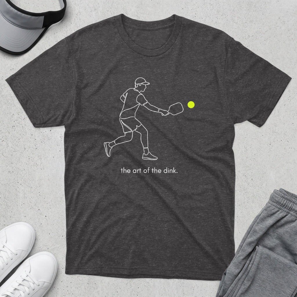Dark t-shirt with white outline of a pickleball player and "the art of the dink" text.
