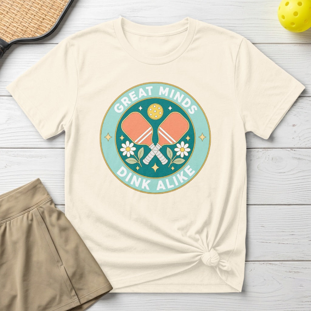Cream t-shirt with "Great Minds Dink Alike" and crossed pickleball paddles graphic.