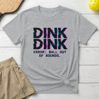 Grey t-shirt with "DINK DINK ERROR: BALL OUT OF BOUNDS" text, light brown skirt.