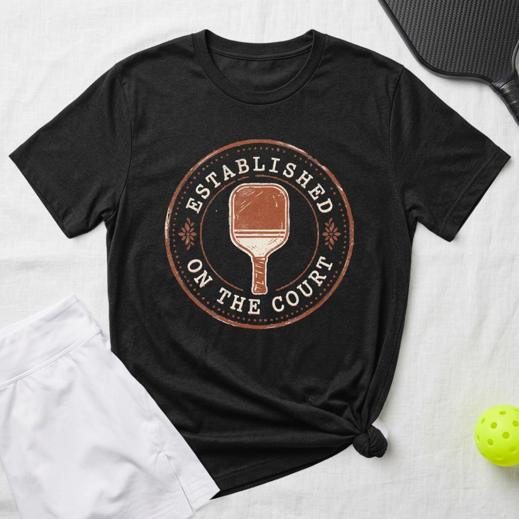 Black t-shirt with distressed "Established on the Court" pickleball paddle graphic.