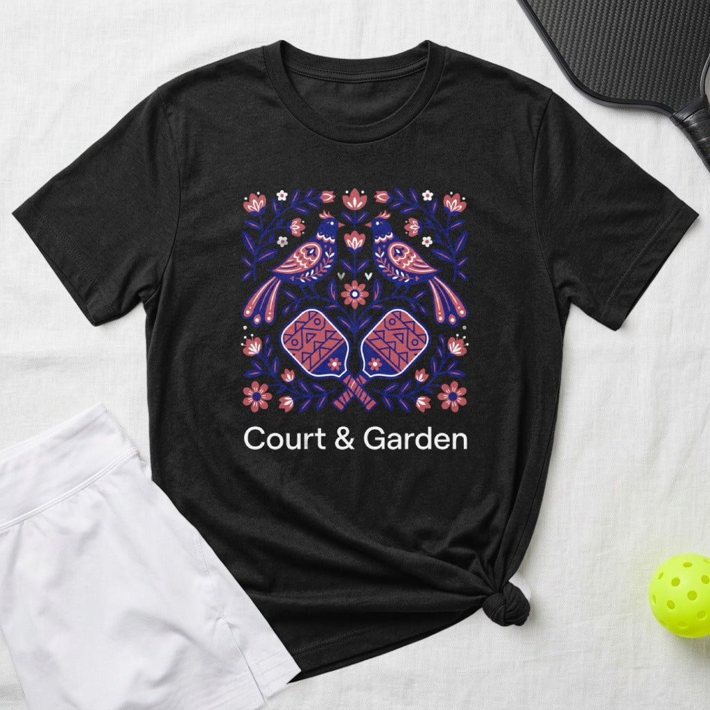 Black t-shirt with a colorful floral and bird design featuring pickleball paddles.