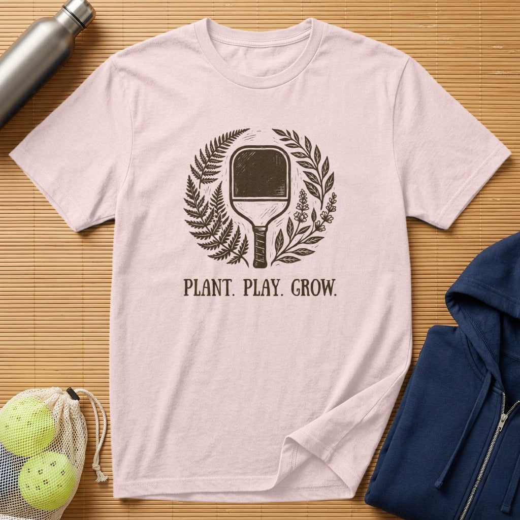 Light pink t-shirt with pickleball paddle and foliage graphic, "Plant. Play. Grow."