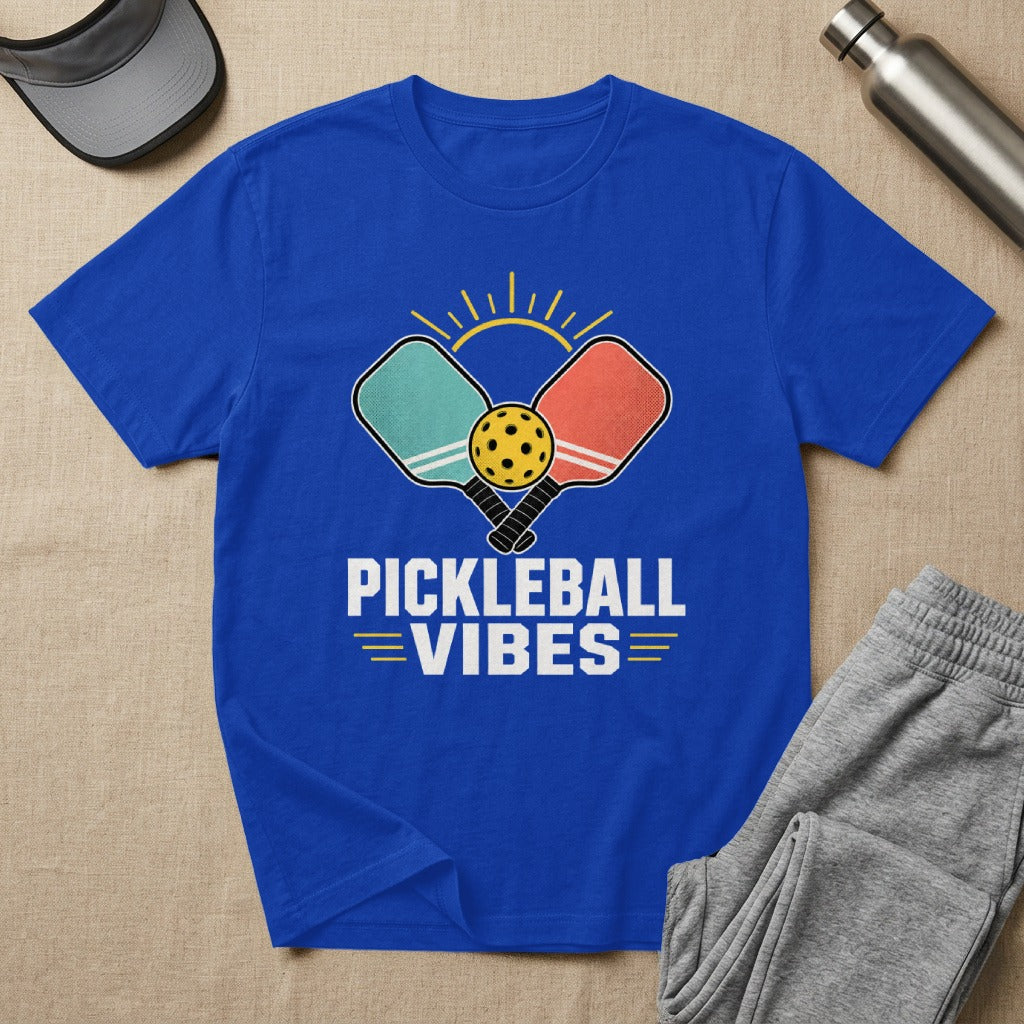Blue t-shirt with coral and teal pickleball paddles, ball, sun, and "Pickleball Vibes" text.