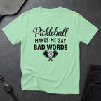 Light green t-shirt with "Pickleball Makes Me Say Bad Words" text and crossed paddles.