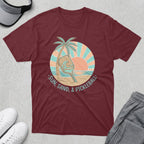 Maroon t-shirt with a circular graphic of a pickleball paddle on a beach at sunset.