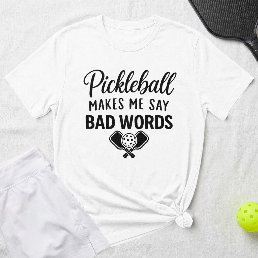 White t-shirt with "Pickleball Makes Me Say Bad Words" graphic and pickleball paddles.
