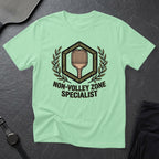 Light green t-shirt with "Non-Volley Zone Specialist" design and pickleball paddle graphic.
