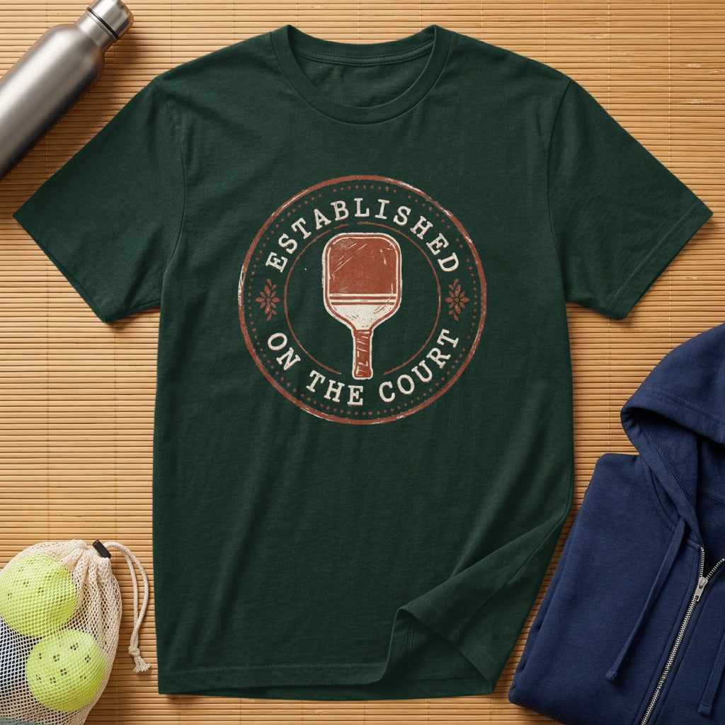 Dark green t-shirt with "Established on the Court" pickleball graphic.