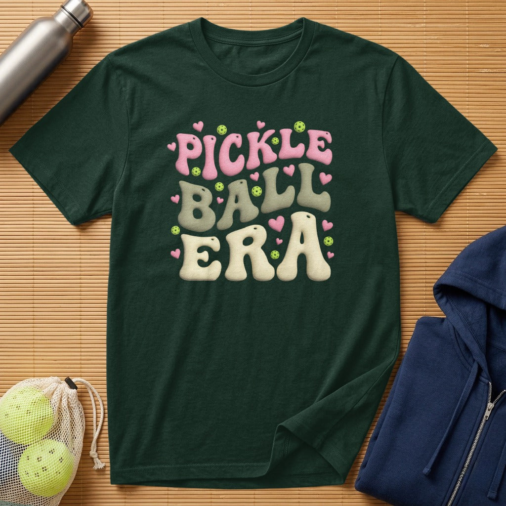 Dark green t-shirt with "Pickle Ball Era" text in pink and cream.