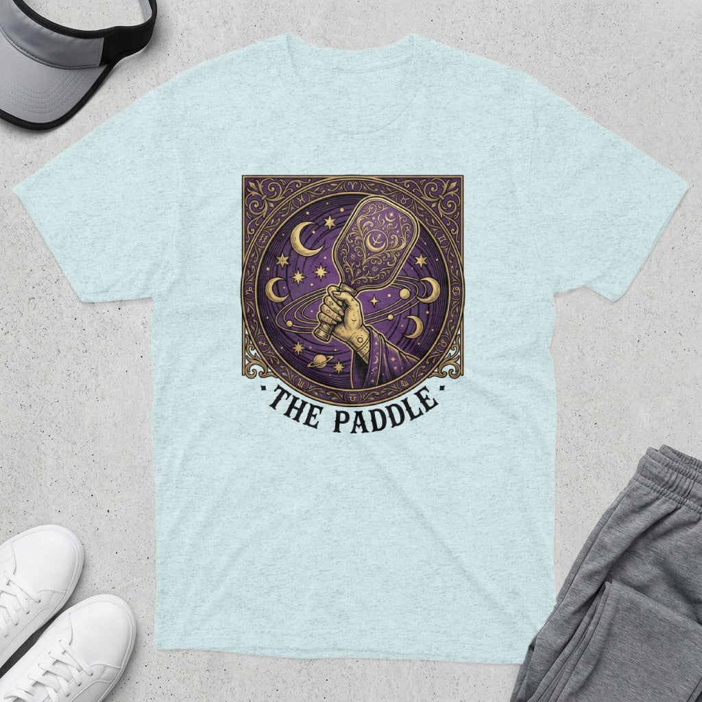 Celestial pickleball paddle design with stars and moons on a light blue t-shirt.