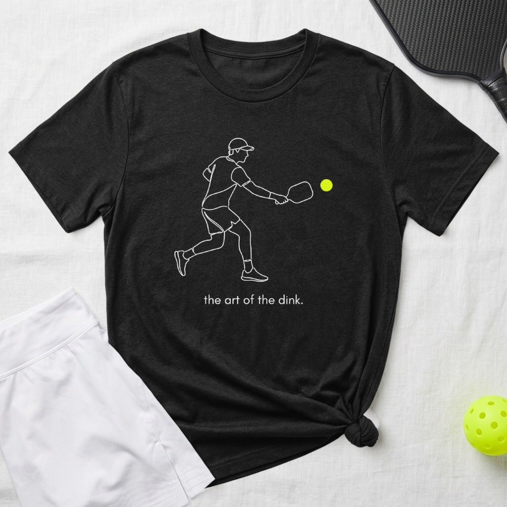 Black t-shirt with white line drawing of a pickleball player and the text "the art of the dink."