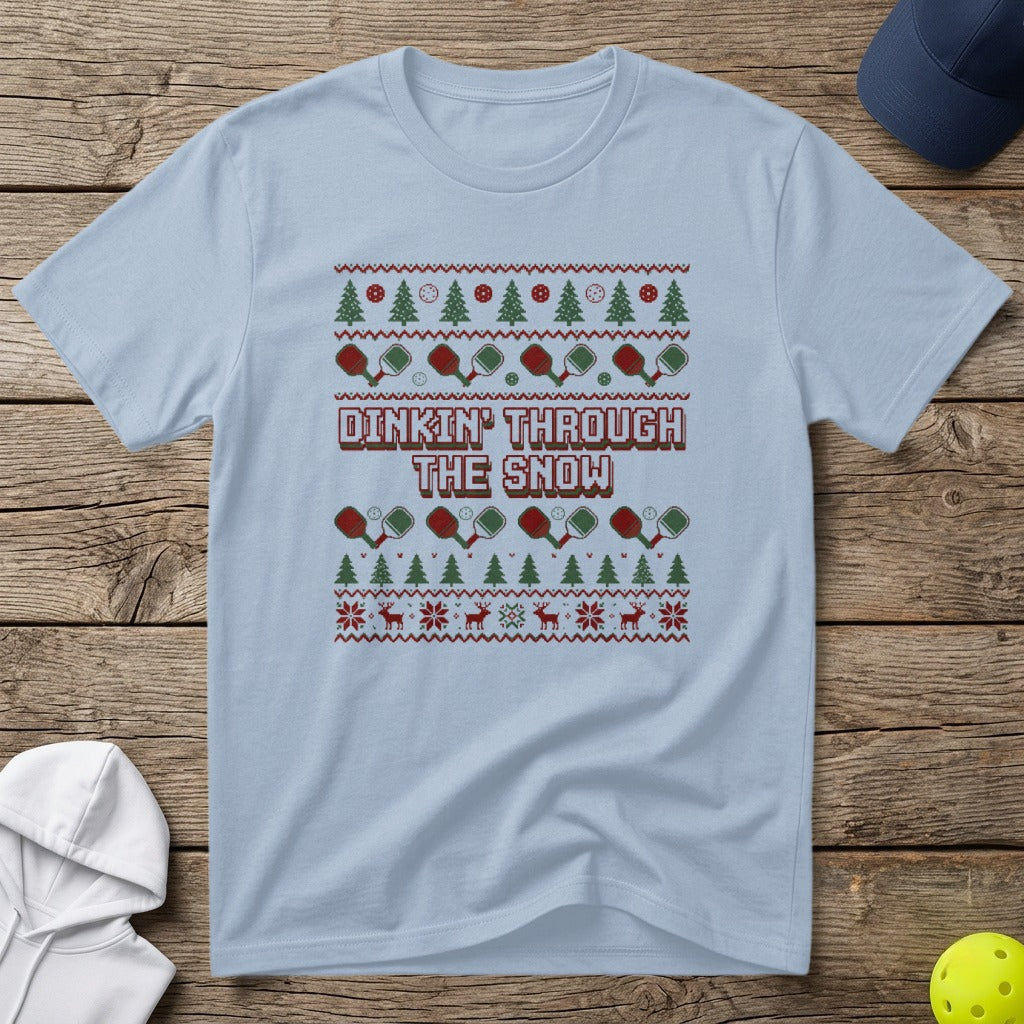 Light blue t-shirt with a holiday-themed pickleball print and text "Dinkin' Through The Snow".