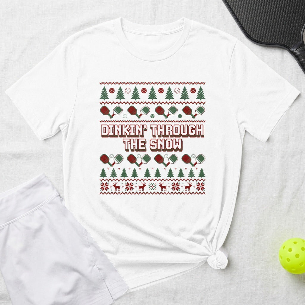 White t-shirt with "Dinkin' Through The Snow" and a Christmas-themed pickleball pattern.