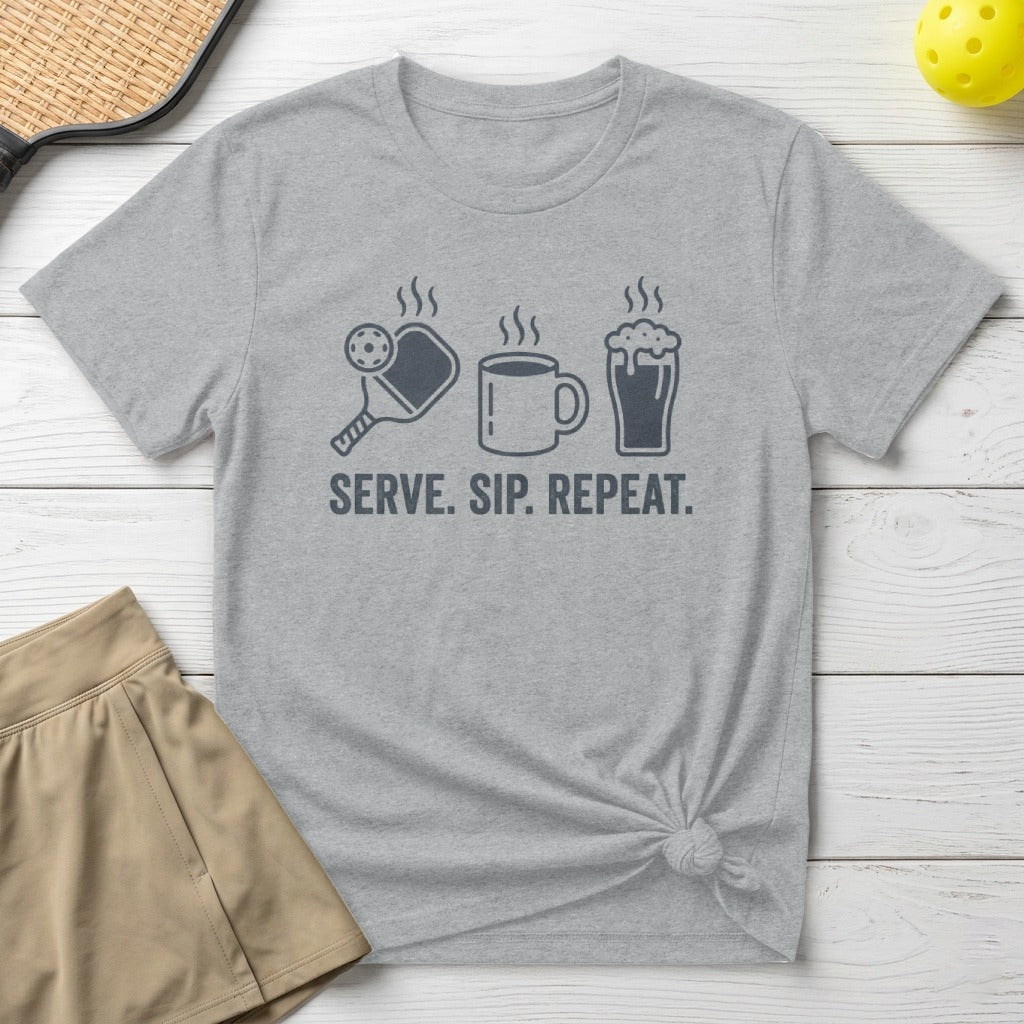 Gray t-shirt with pickleball, coffee cup, and beer mug icons and text "SERVE. SIP. REPEAT."