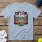 Light blue t-shirt with "VISIT THE KITCHEN" and desert tennis court graphic.