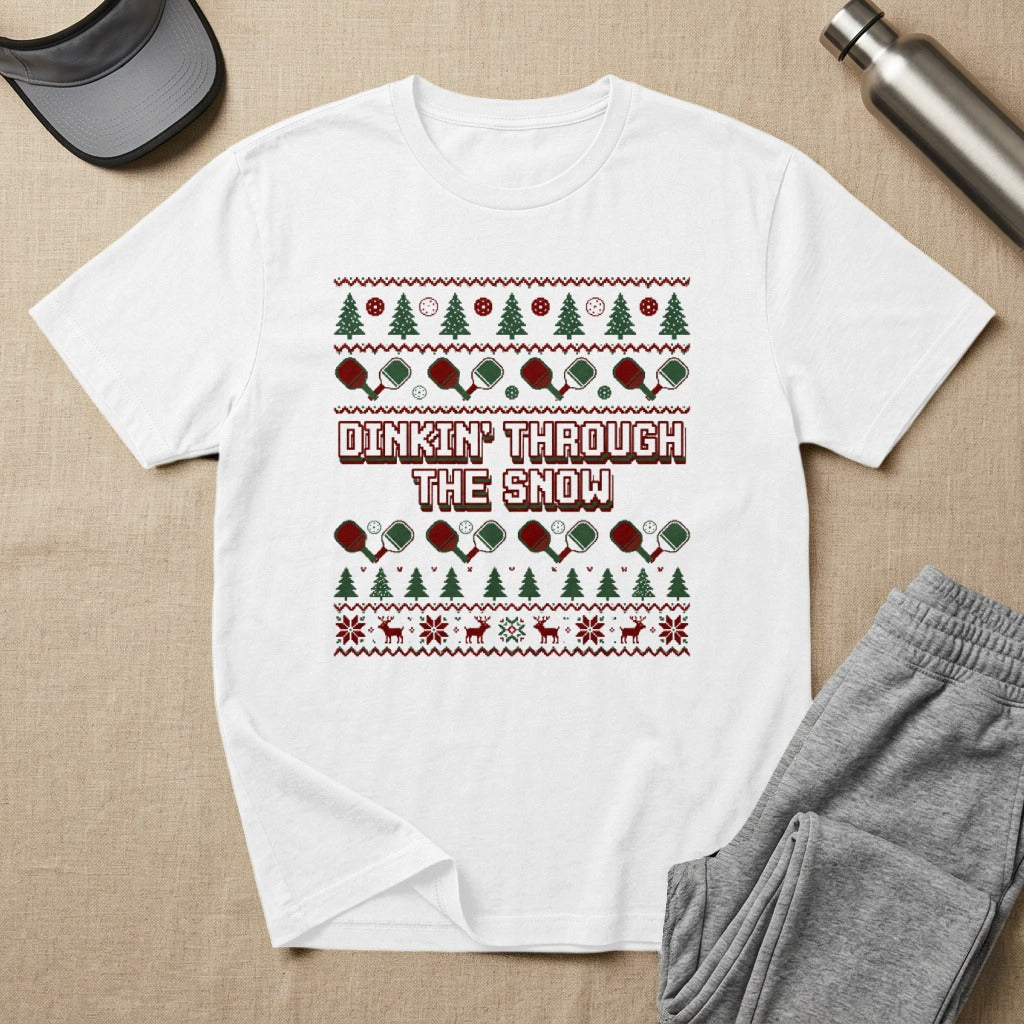 White t-shirt with "Dinkin' Through the Snow" text and festive Christmas pickleball design.