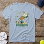 Light blue t-shirt with "Pickleball Paradise" text and rocket launching a pickleball.