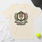 Cream t-shirt with "Non-Volley Zone Specialist" graphic and pickleball equipment.