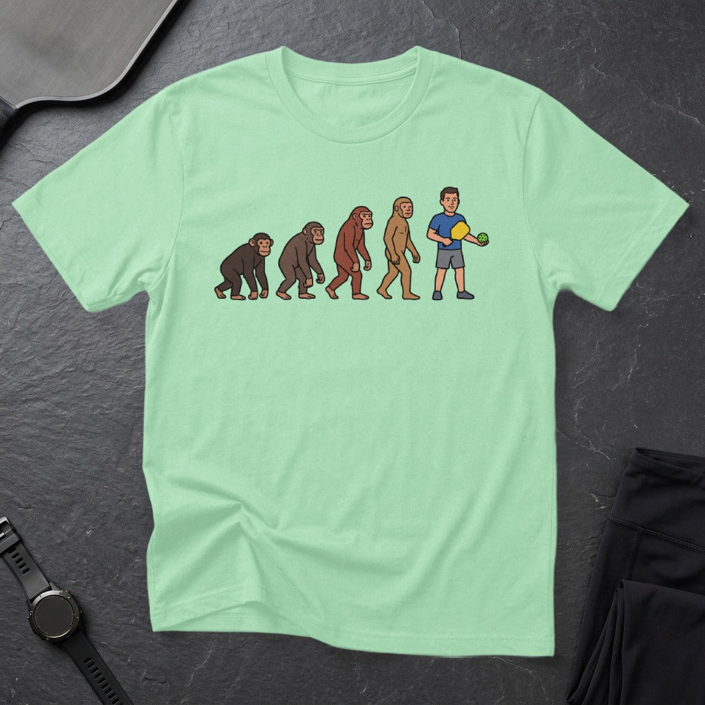 T-shirt with cartoon evolution of man holding a pickleball paddle.