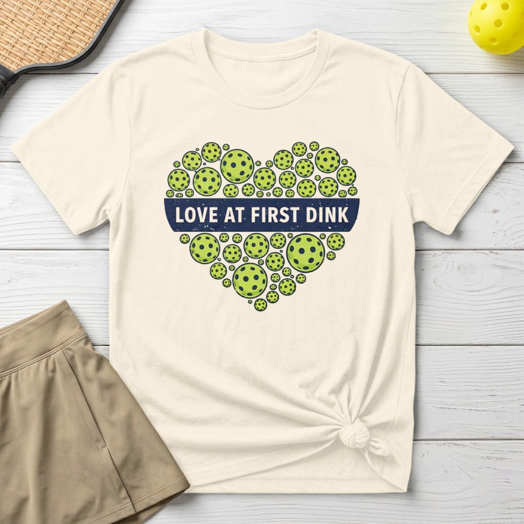 White t-shirt with a heart made of pickleballs and "Love at First Dink" text.