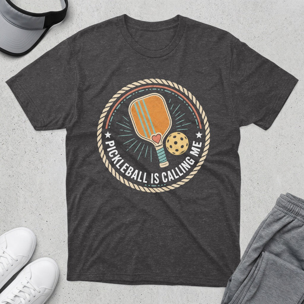 Dark grey t-shirt with a pickleball paddle, ball, and text "Pickleball is Calling Me".