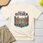 T-shirt graphic: pickleball court in desert with "VISIT THE KITCHEN." text.