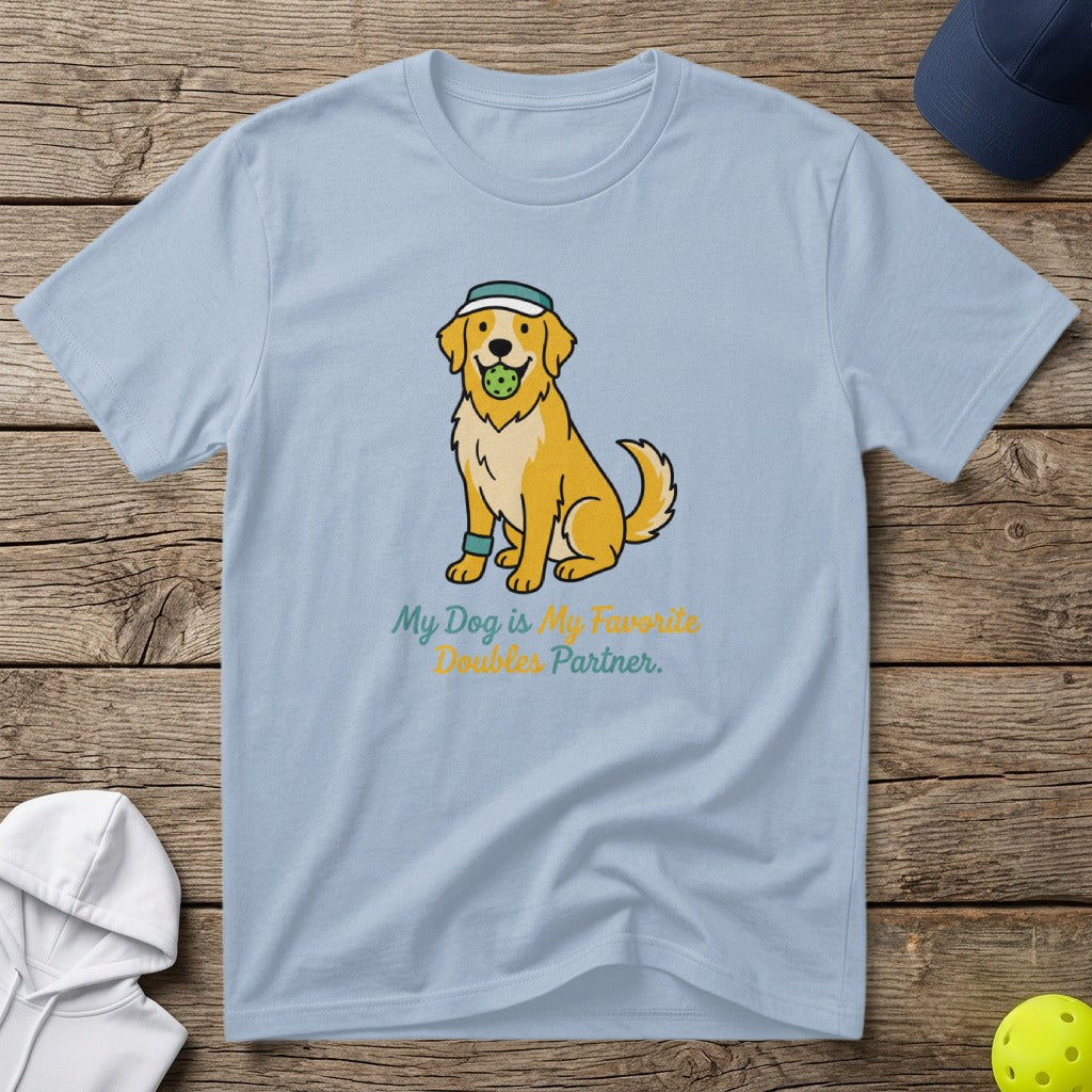 Light blue t-shirt with a cartoon golden retriever wearing a hat and holding a tennis ball, text reads "My Dog is My Favorite Doubles Partner."
