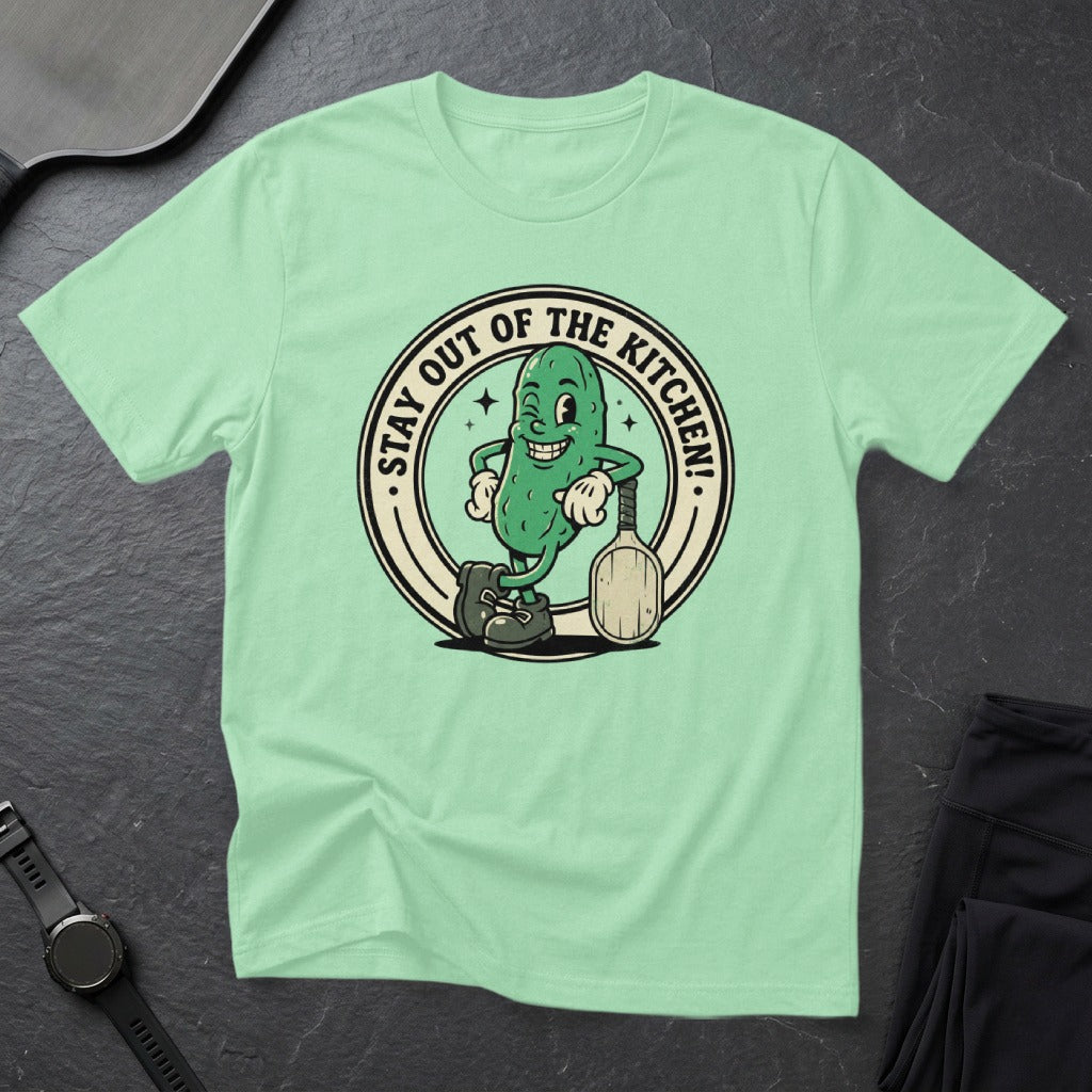 Green t-shirt with cartoon pickle holding a pickleball paddle.