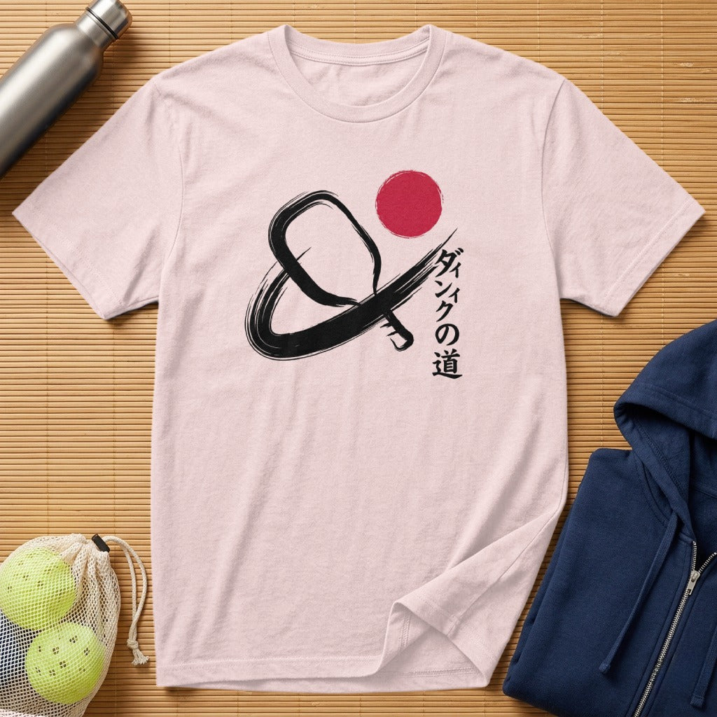 Black pickleball paddle and ball graphic with Japanese text on a pink t-shirt.