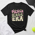Black t-shirt with "Pickle Ball Era" in colorful, bubbly font and heart accents.