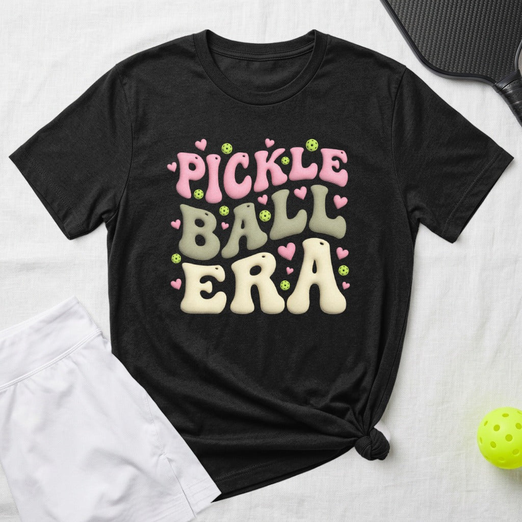 Black t-shirt with "Pickle Ball Era" in colorful, bubbly font and heart accents.